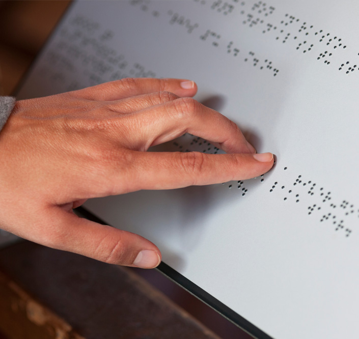 A person's hand touching braille text