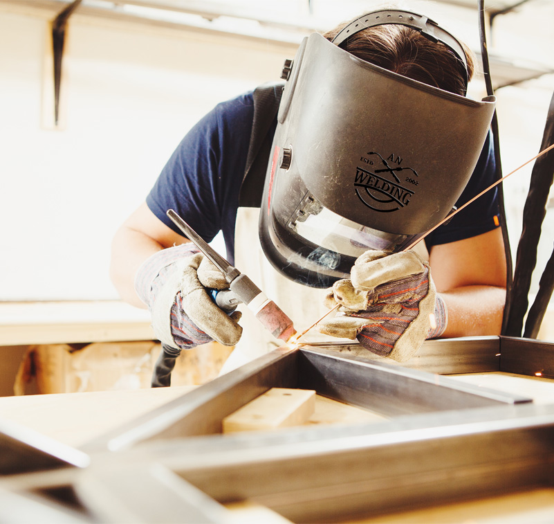 A person welding a piece of wood wearing a personalised welding mask
