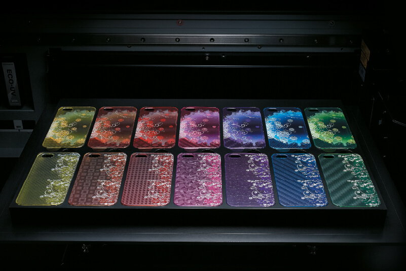 Una impresora de mesa plana con fundas de móvil multicolores personalizadas