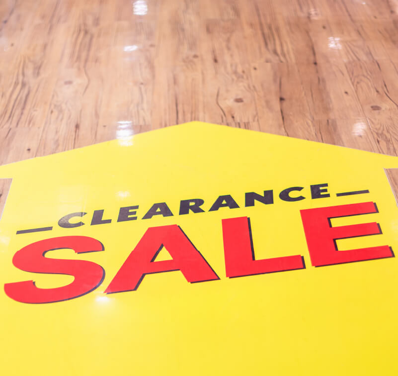 A large floor sticker in the shape of an arrow with ‘clearance sale’ printed on it