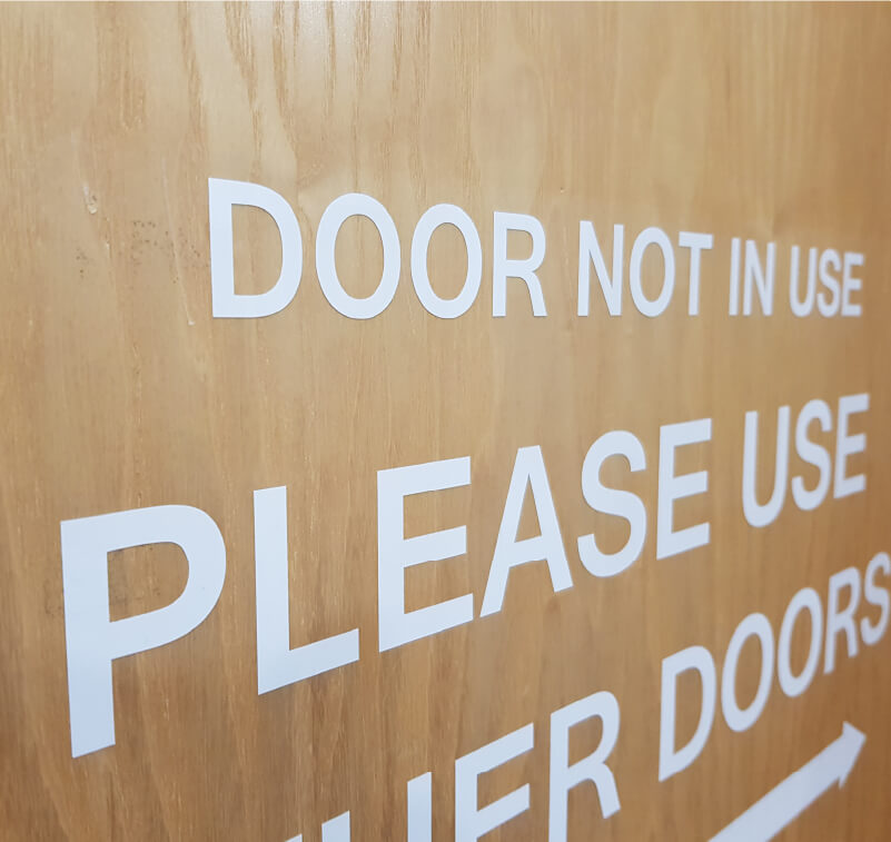 Aus selbstklebender Folie ausgeschnittene Buchstaben wurden auf eine Tür geklebt und werden so zu einem Hinweis.