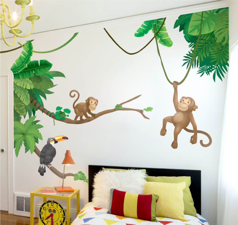 Eine Wand in einem Kinderzimmer mit Aufklebern in Form von Affen und einem Tukan