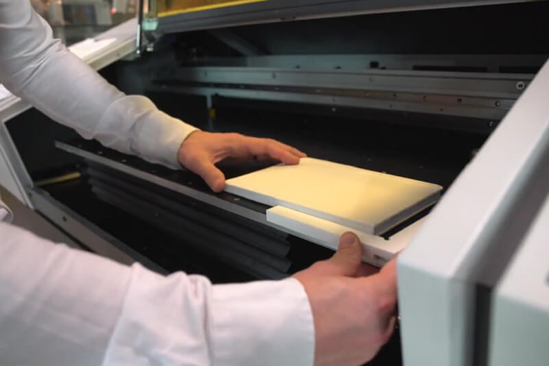 Positionieren eines leeren Notizbuchs auf einem Flachbett-UV-Drucker mit einer Kantenführung.
