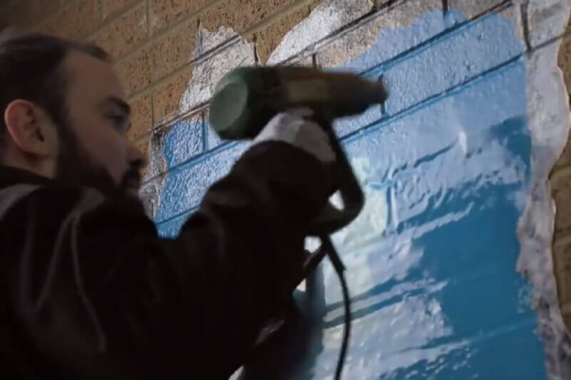 Using a heat gun to apply an exterior sticker on an uneven wall