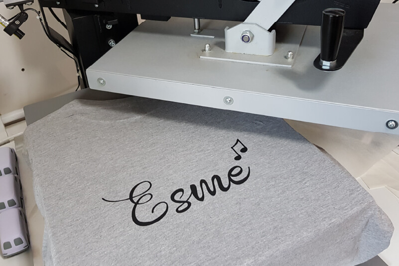 A t-shirt on a heat press with custom-printed text