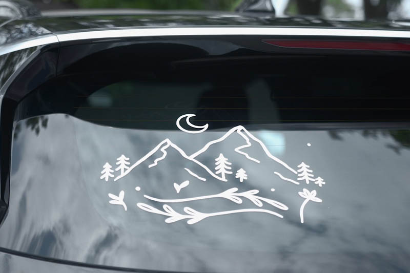Adhesivo de paisaje montañoso aplicado sobre la ventana de un coche