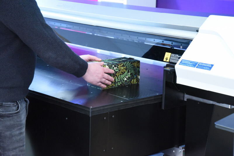Pose d’une boîte sur le plateau d’une imprimante UV à plat
