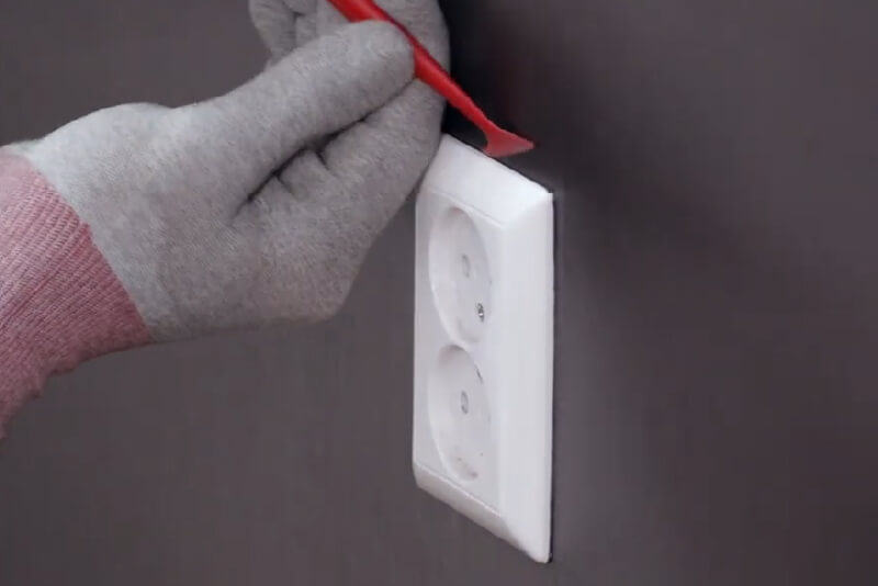 Using a FleXtreme micro-squeegee to mould vinyl around an electrical socket (Source: Avery Dennison)