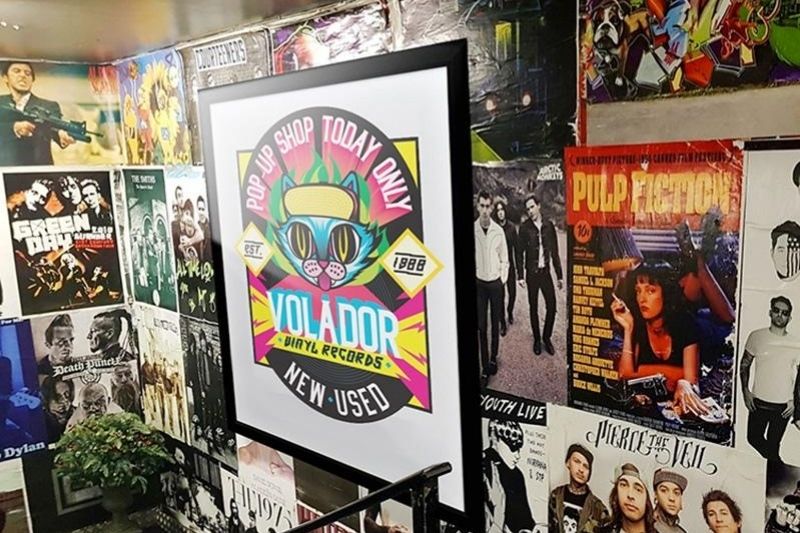 Printed poster in a frame hanging in a music shop with a background of album cover posters