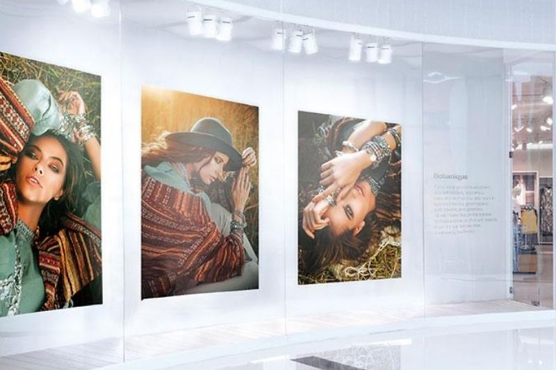 Три ярких изображения моделей, распечатанные на принтере для УФ-печати и размещенные у фасада розничного магазина