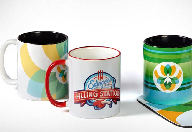 Three branded mugs with corporate logos and company designs