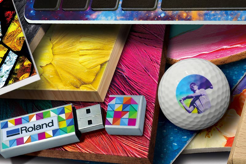USB stick branded with corporate Roland logo, golf ball and other items printed on a UV printer