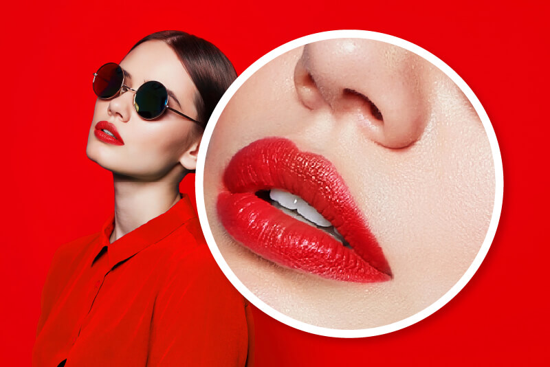 Vrouw met rode lippen en een donkere bril, die ook in het rood gekleed is en voor een rode muur staat. De afbeelding heeft ook een witte cirkel die inzoomt op de rode lippen van de vrouw om de rode kleur en structuur van de lippen te benadrukken.
